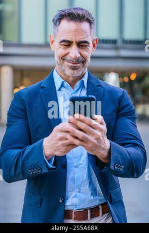 Confident businessman using smartphone outdoors.Vertical Stock Photo