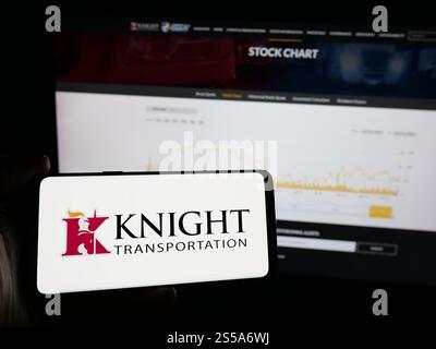 In this photo illustration, a person is holding a mobile phone with the logo of Knight-Swift Transportation Holdings Inc. on screen in front of web page. (Photo by Timon Schneider / SOPA Images/Sipa USA) *** Strictly for editorial news purposes only *** Stock Photo