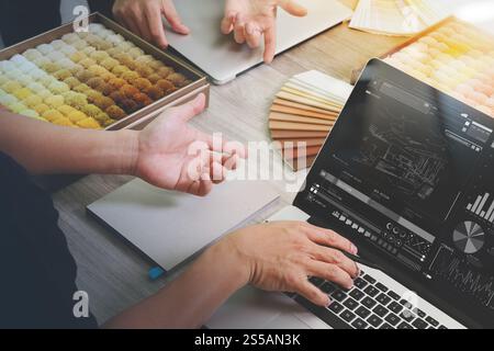 top view of two colleagues interior designers discussing data with design diagram on new modern computer laptop screen with sample material on wooden Stock Photo