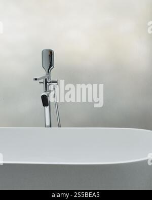Close-up of a chrome tap next to a white ceramic bathtub Stock Photo