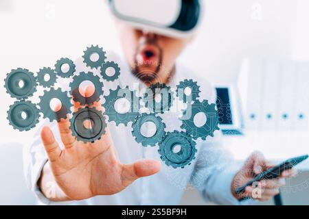 businessman wearing virtual reality goggles in modern office with mobile phone using with VR headset with 3d gear of success Stock Photo