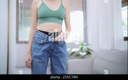 Asian woman dieting Weight loss. Slim woman in oversize jeans . Stock Photo