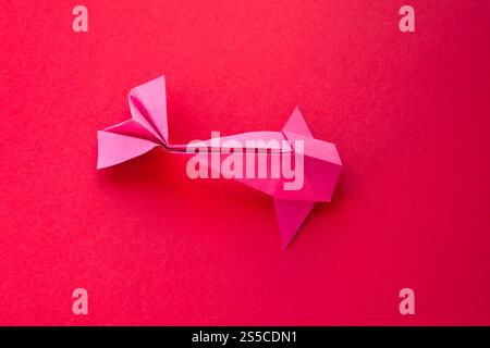 Pink paper fish origami isolated on a blank red background. Pink paper fish origami isolated on a red background Stock Photo