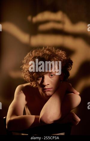 Vertical portrait of young adult cure red haired man sitting and posing for portrait in studio Stock Photo