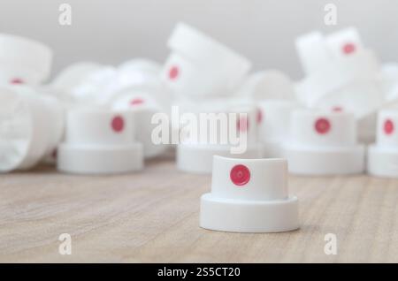 Several new plastic nozzles from a paint sprayer that lie on a wooden surface against a gray wall background. The concept of street art and graffiti Stock Photo
