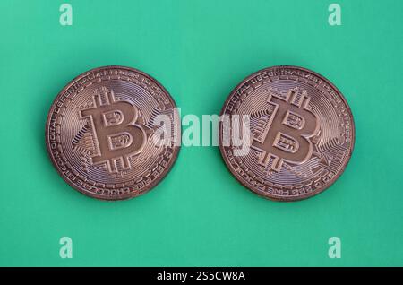 Two chocolate products in the form of physical bitcoins lie on a green plastic background. Model of the crypto currency in the edible form Stock Photo