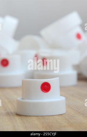 Several new plastic nozzles from a paint sprayer that lie on a wooden surface against a gray wall background. The concept of street art and graffiti Stock Photo