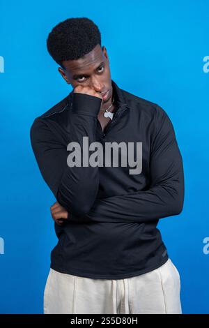 Bored young man with hand on his face showing apathy posing on blue background Stock Photo