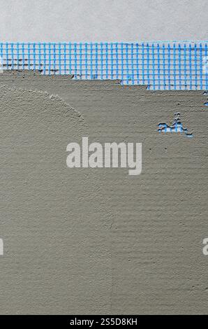 The texture of the wall, covered with gray foam polystyrene plates, covered with a blue reinforcing mesh and covered with a mixture for gluing it. Stock Photo