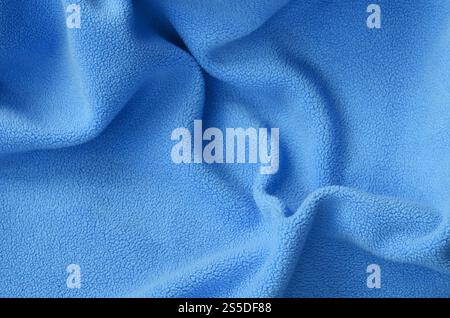 The blanket of furry blue fleece fabric. A background of light blue soft plush fleece material with a lot of relief folds Stock Photo