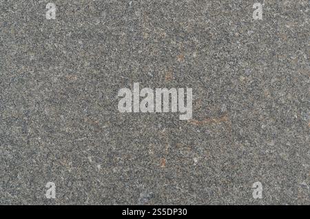 Monochromatic texture of granite surface. Detailed photo of the treated glossy granite stone, which is used as tiles for walls and floors. Stock Photo