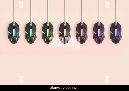 Several computer mice hang on a pastel peach background. The concept of cooperative computer video games, the use of auto-clicker and pay-per-click Stock Photo