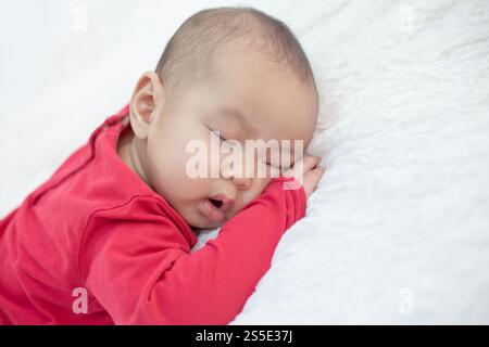 Babies wearing red shirts sleeping in bed Stock Photo