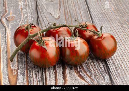 kumato cherry tomato branch on wood background Stock Photo