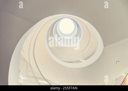 White spiral staircase leading up to a round skylight in a modern building, viewed from below, in the university library of Helsinki Stock Photo