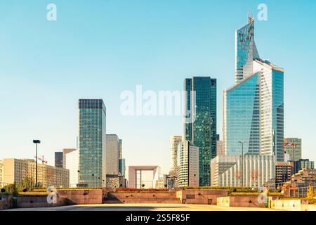 Modern skyscrapers dominate the skyline under a clear blue sky with a pedestrian walkway in the foreground in La Defense, Paris, France Stock Photo