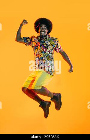 African man portrait in studio on colorful background - Cool black young male with stylish attire posing , creative colored lighting Stock Photo