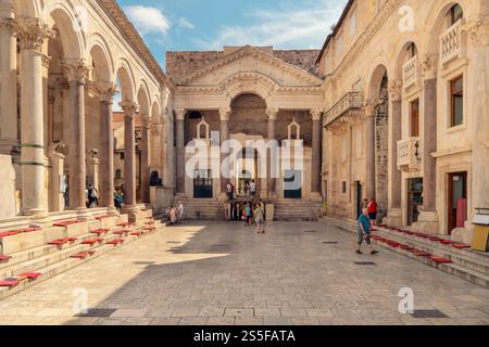 Tourists gather at a historic square with the Diocletian's Palace, exploring and taking photos on a sunny day, Split, Croatia Stock Photo
