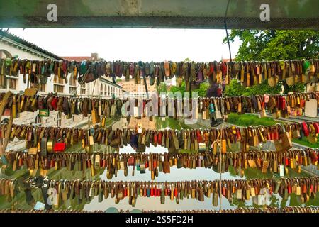 Rows of various antique locks and keys displayed on a sunny day with trees and buildings reflecting off the Ljubljana River, Ljubljana, Slovenia Stock Photo
