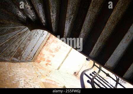 Spiral staircase in an old building with rusted metal steps and aged brick walls illuminated by natural light, Berlin, Germany Stock Photo
