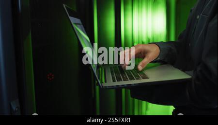 Image of man using laptop over computer servers Stock Photo