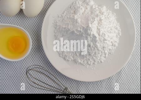 Eggs, tapioca flour and an egg beater, ingredients used in bakery Stock Photo