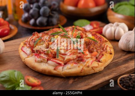 Pizza placed on a wooden plate complete with pepper seeds. Tomatoes and garlic. Selective focus. Stock Photo