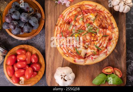 Pizza placed on a wooden plate complete with pepper seeds. Tomatoes and garlic. Top view. Stock Photo
