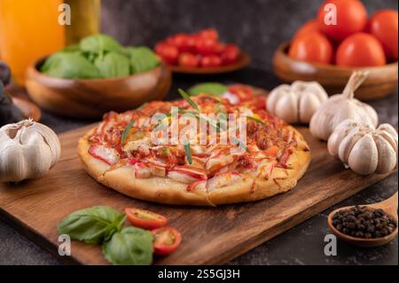 Pizza placed on a wooden plate complete with pepper seeds. Tomatoes and garlic. Selective focus. Stock Photo