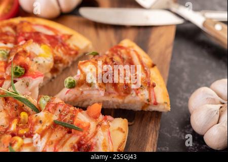 Pizza placed on a wooden plate complete with pepper seeds. Tomatoes and garlic. Selective focus. Stock Photo