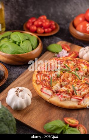 Pizza placed on a wooden plate complete with pepper seeds. Tomatoes and garlic. Selective focus. Stock Photo