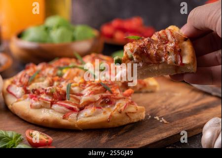 Pizza placed on a wooden plate complete with pepper seeds. Tomatoes and garlic. Selective focus. Stock Photo