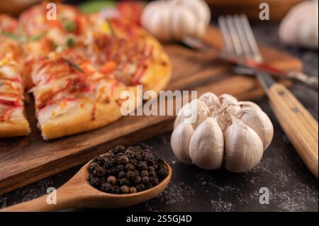 Pizza placed on a wooden plate complete with pepper seeds. Tomatoes and garlic. Selective focus garlic. Stock Photo