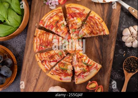 Pizza placed on a wooden plate complete with pepper seeds. Tomatoes and garlic. Top view. Stock Photo