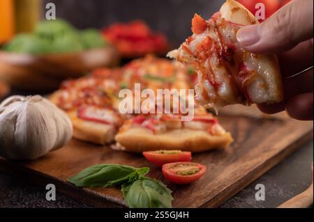 Pizza placed on a wooden plate complete with pepper seeds. Tomatoes and garlic. Stock Photo
