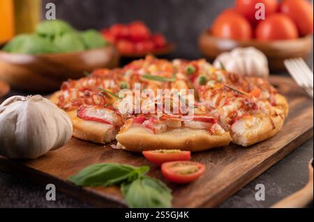 Pizza placed on a wooden plate complete with pepper seeds. Tomatoes and garlic. Stock Photo