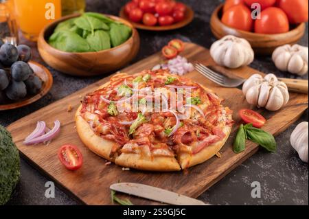 Pizza placed on a wooden plate complete with pepper seeds. Tomatoes and garlic. Selective focus. Stock Photo