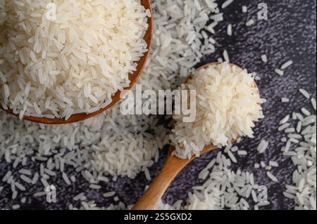 Milled rice in a bowl and a wooden spoon on the black cement floor. Top view Stock Photo