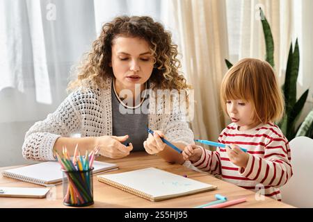 A mother and her daughter engage in a fun drawing session, bonding through creativity at home. Stock Photo