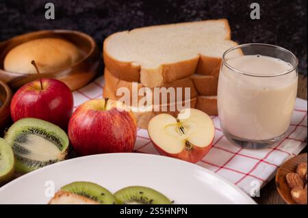 Apples, kiwi, milk and bread in a plate on a red white cloth. Selective focus. Stock Photo