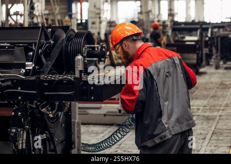 Industrial worker assembles agricultural machine in workshop. Stock Photo
