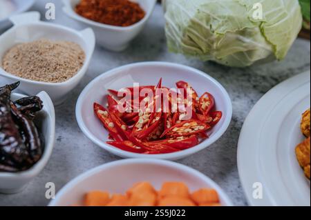 Diced carrots, dried chilies, roasted rice, chili, and cabbage are placed on a cement floor Stock Photo