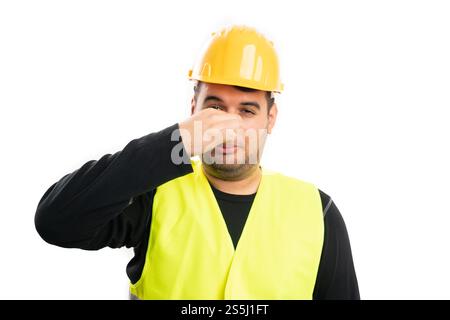 Male construction worker holding nose as bad smell stench concept wearing work equipment isolated on white studio background Stock Photo