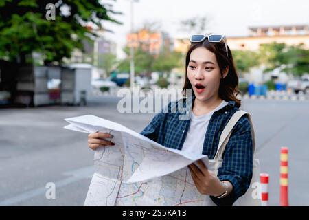 Young tourist female holding and checking on paper map, She looking with excited and happy Stock Photo