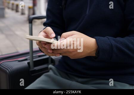 Man in downtown city street ordering taxi using smart phone app Booking taxi using application online on smart phone. Stock Photo