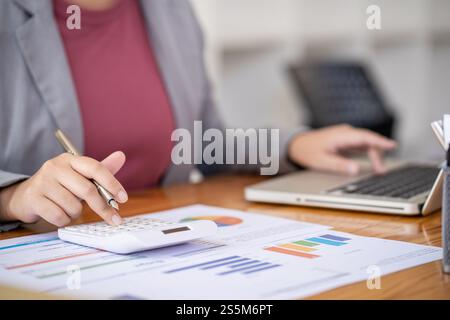 Businesswoman Accountant analyzing investment charts Invoice and pressing calculator buttons over documents. Accounting Bookkeeper Clerk Bank Advisor Stock Photo