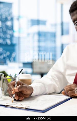 Man signing contract after being vetted by HR employee ensuring skills match role needs. Person filling application form after headhunter assessed his previous work experience Stock Photo