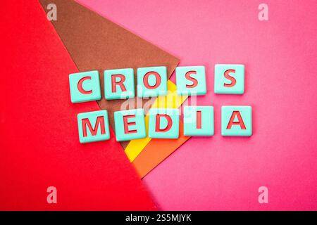 CROSS MEDIA. Alphabet letter tiles on a red textured background. Stock Photo