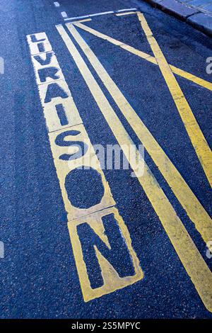 Road marking "LIVRAISON" written in French (meaning "DELIVERY") along a parking space reserved for deliveries on a street in Paris, France Stock Photo