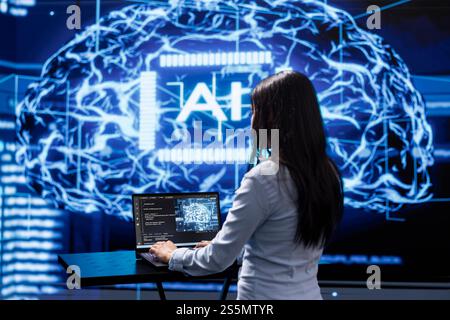 Programmer analyzing complex AI brain models on laptop, running simulations. Female employee using machine learning software on notebook device to develop artificial intelligence technology Stock Photo